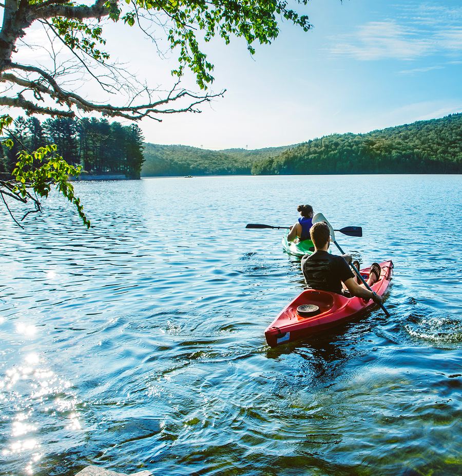 Personne en kayak sur un lac entouré de collines boisées