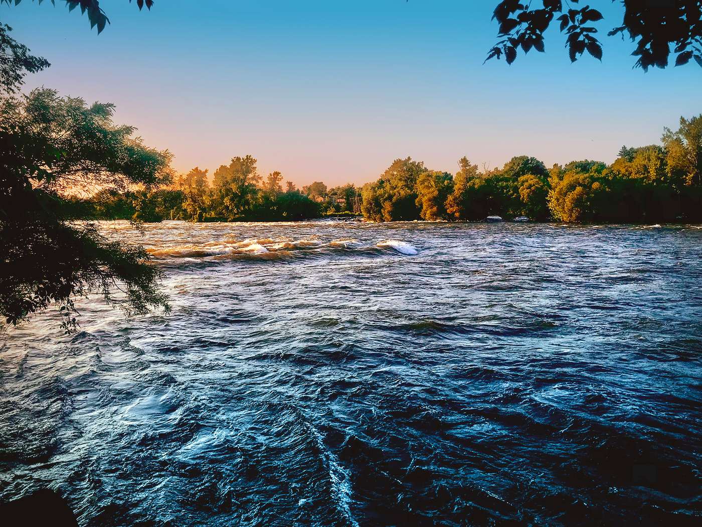 Rivière Richelieu au coucher du soleil, eau vive entourée d'arbres